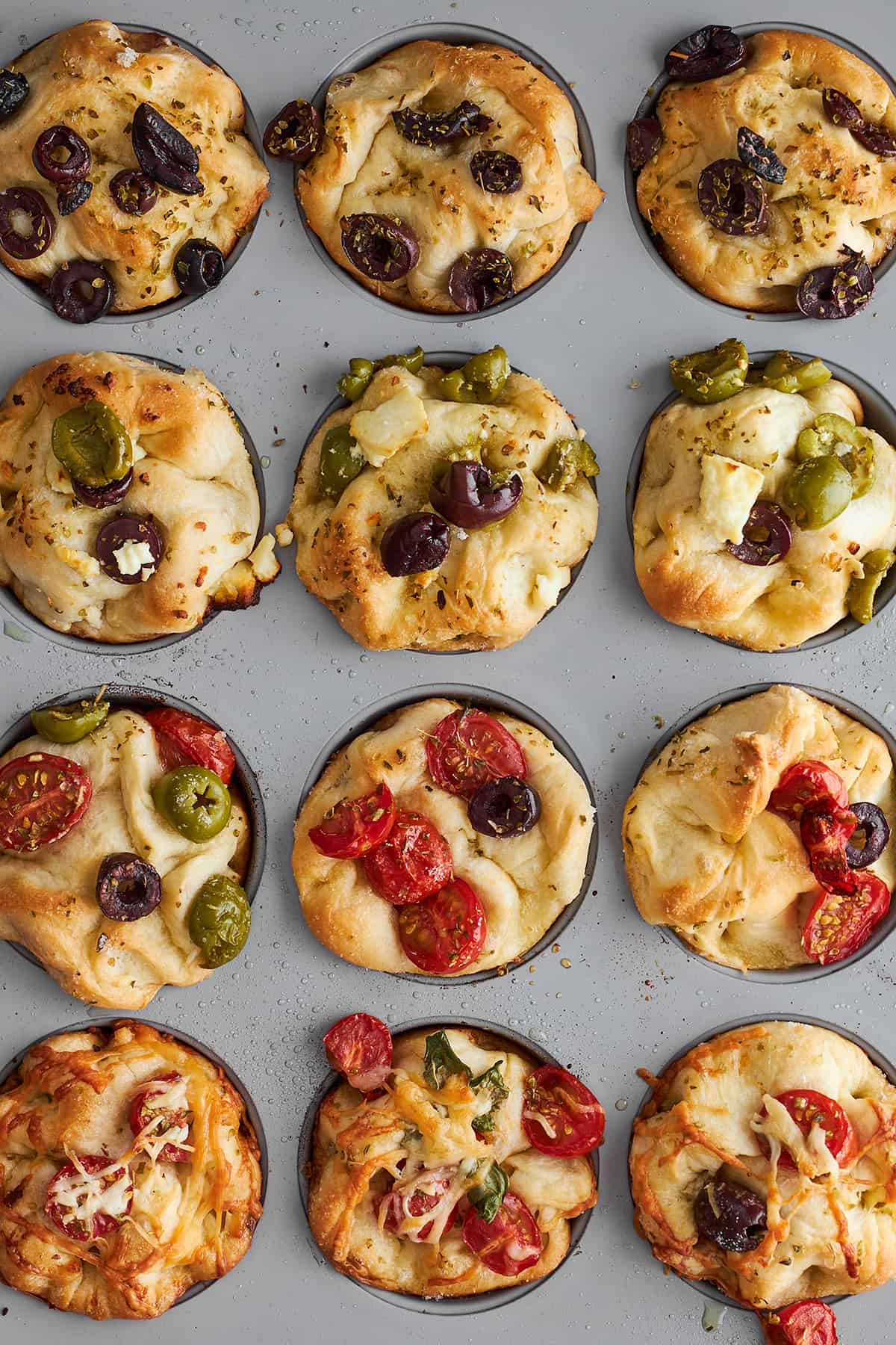 Baked focaccia muffins in a muffin tin.