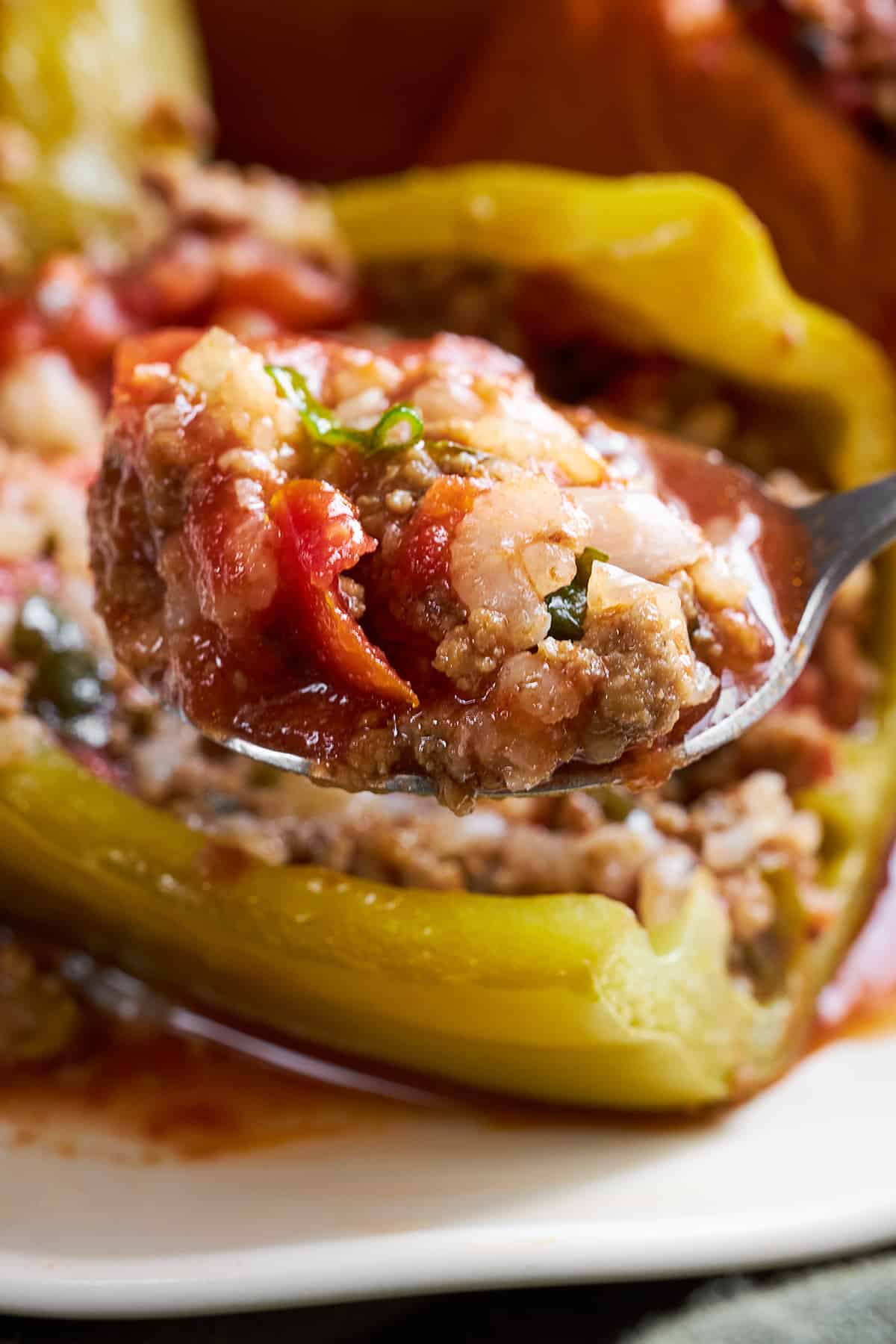 A spoon lifting a bite of filling from a stuffed pepper with rice.
