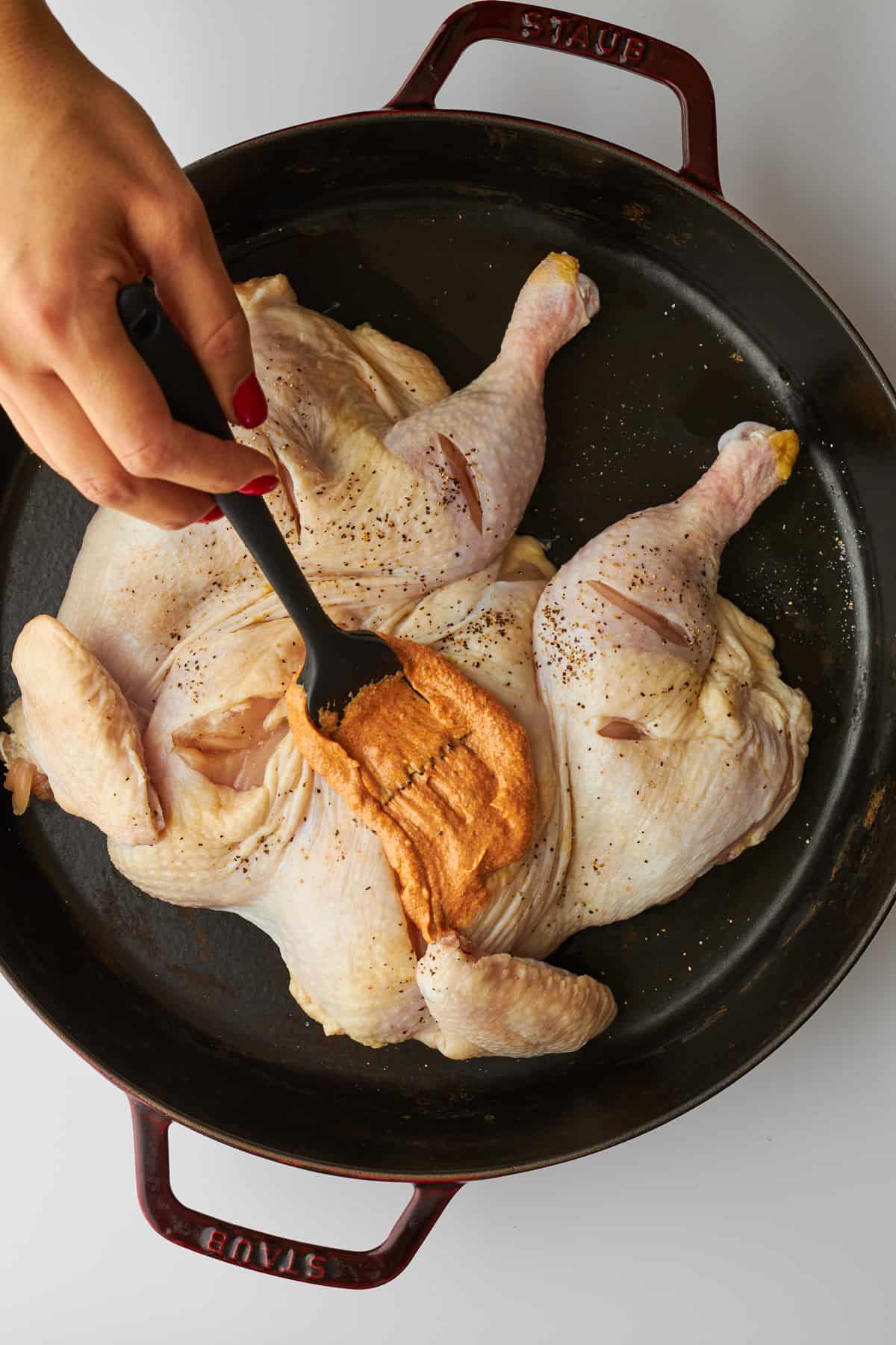 Chicken tikka marinade being brushed over a spatchcock chicken. 