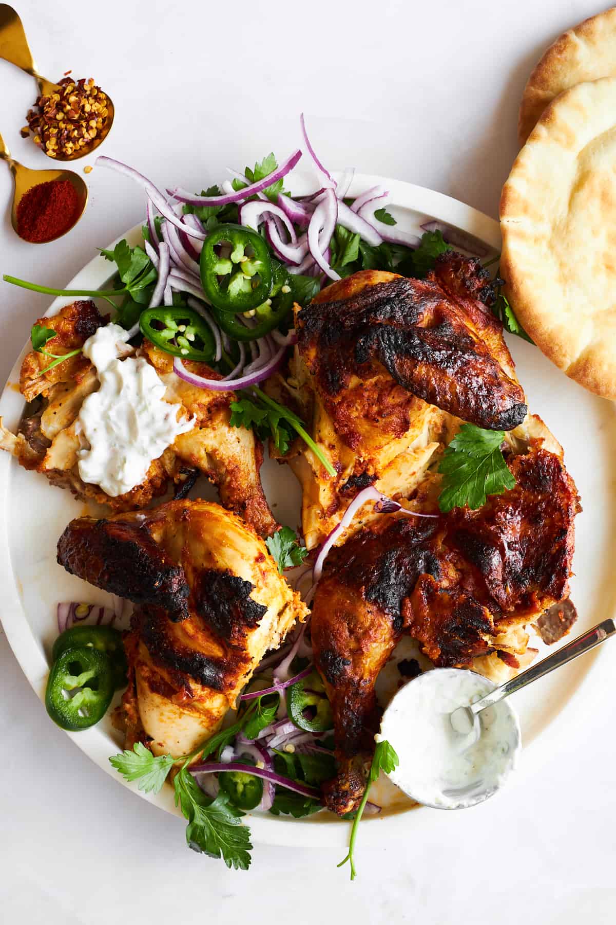 Pieces of chicken tikka on a plate with garnishes. 