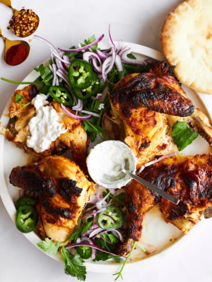 Four pieces of chicken tikka on a plate with garnishes.