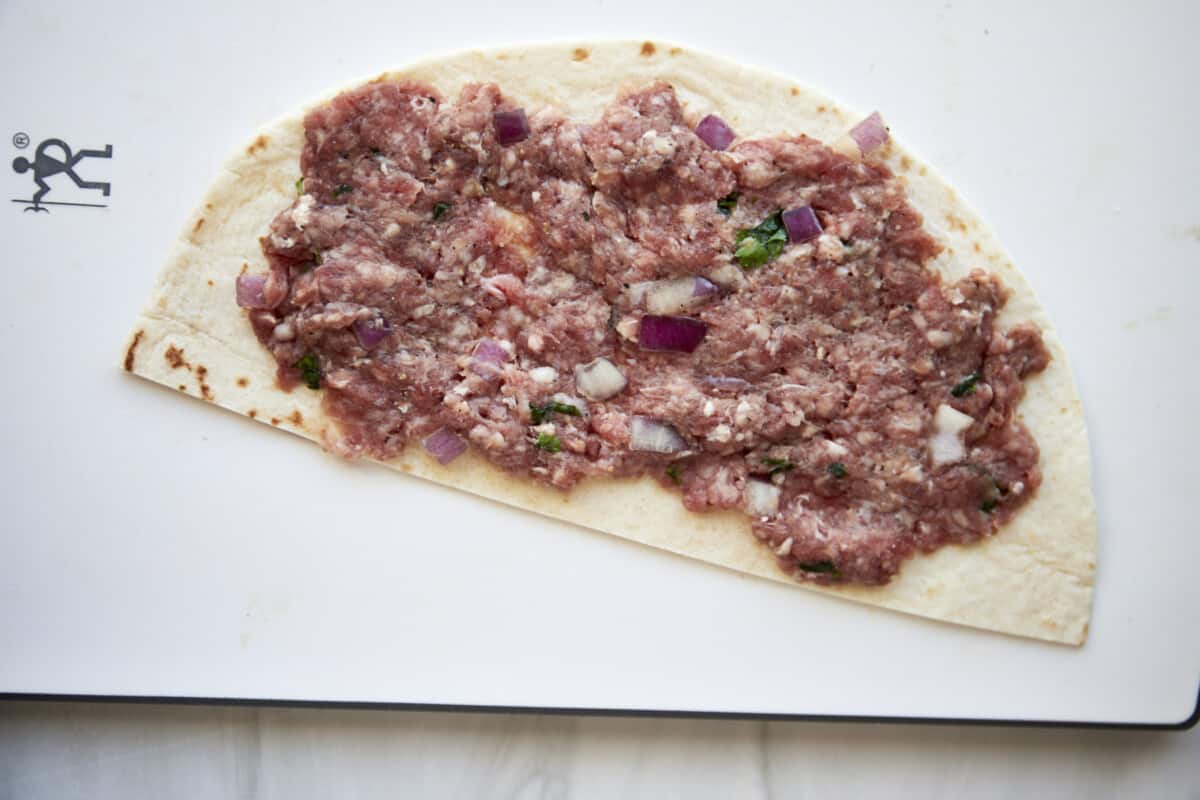 Ground beef spread over a tortilla half. 