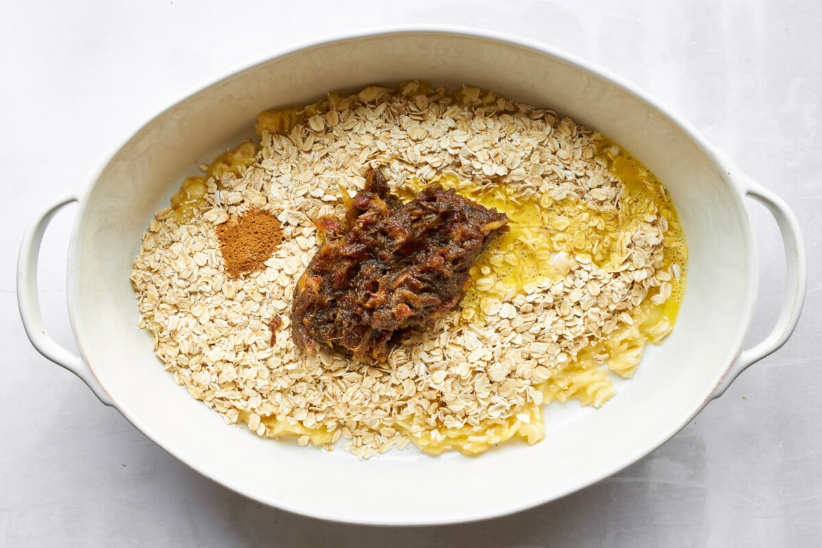 Mashed bananas, oats, date paste, and cinnamon in an oval baking dish.