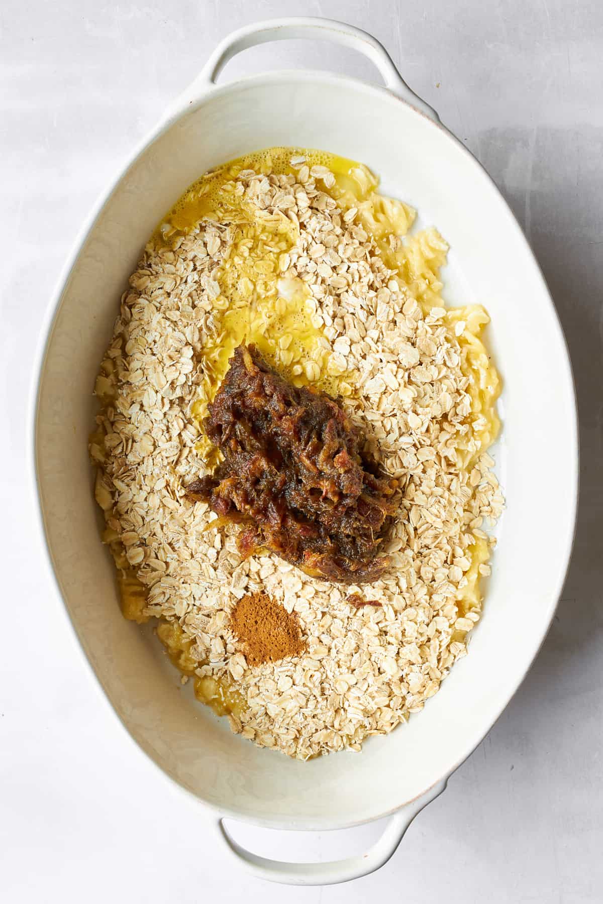 Ingredients for banana date oatmeal in an oval baking dish. 