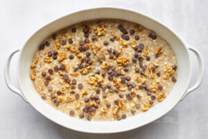 Unbaked banana date oatmeal with chocolate chips in an oval baking dish.