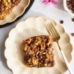 A square of banana date oatmeal on a plate with a fork.