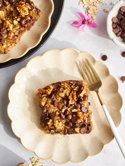 A square of banana date oatmeal on a plate with a fork.