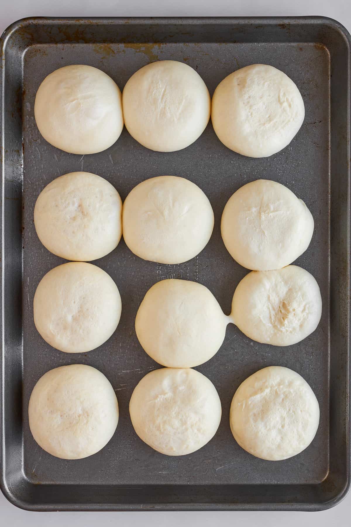 Raw dinner rolls on a baking sheet. 