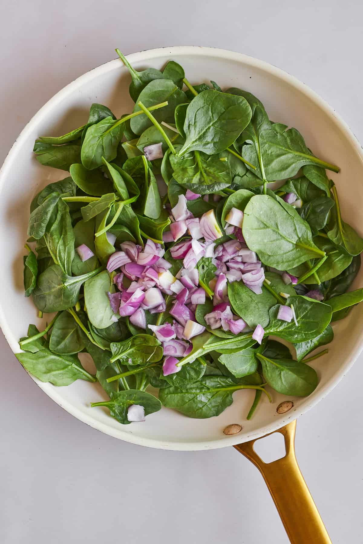 Spinach and shallot sautéeing in a skillet. 