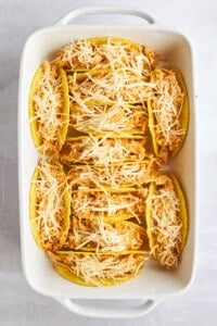Hard taco shells stuffed with shawarma chicken and cheese in a baking dish.