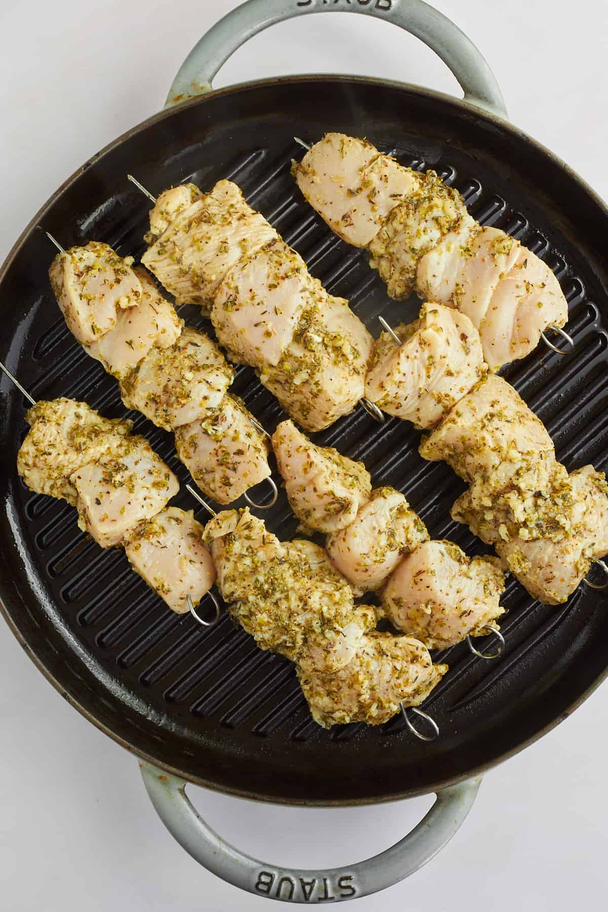 Chicken souvlaki skewers cooking on a grill pan. 