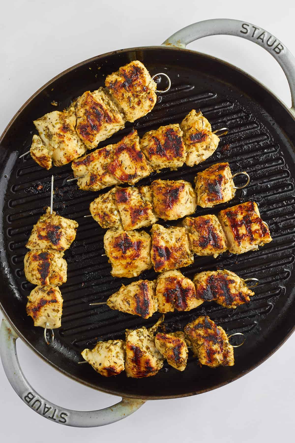 Grilled chicken souvlaki skewers on a grill pan.