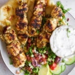 A plate of Greek chicken souvlaki skewers with salad.