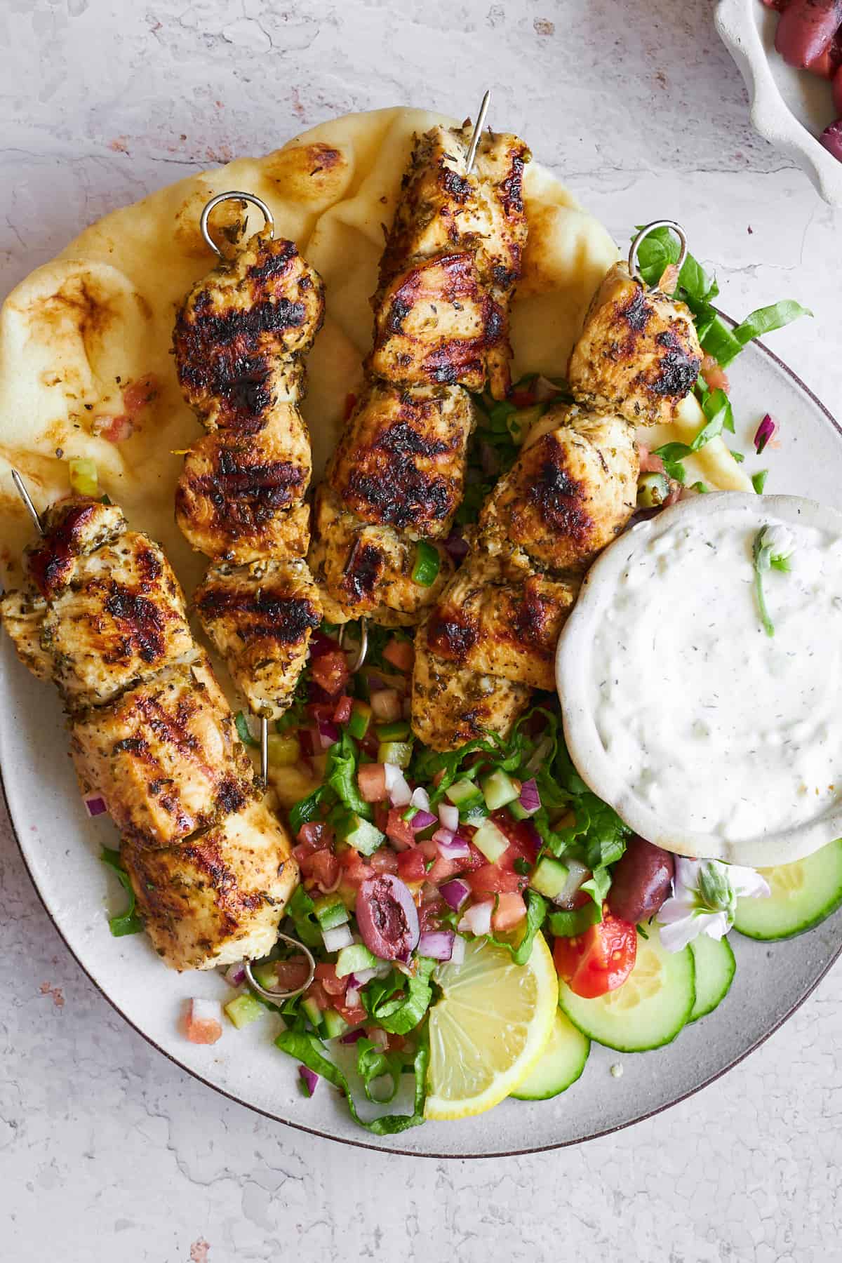 A plate of Greek chicken souvlaki skewers with salad.