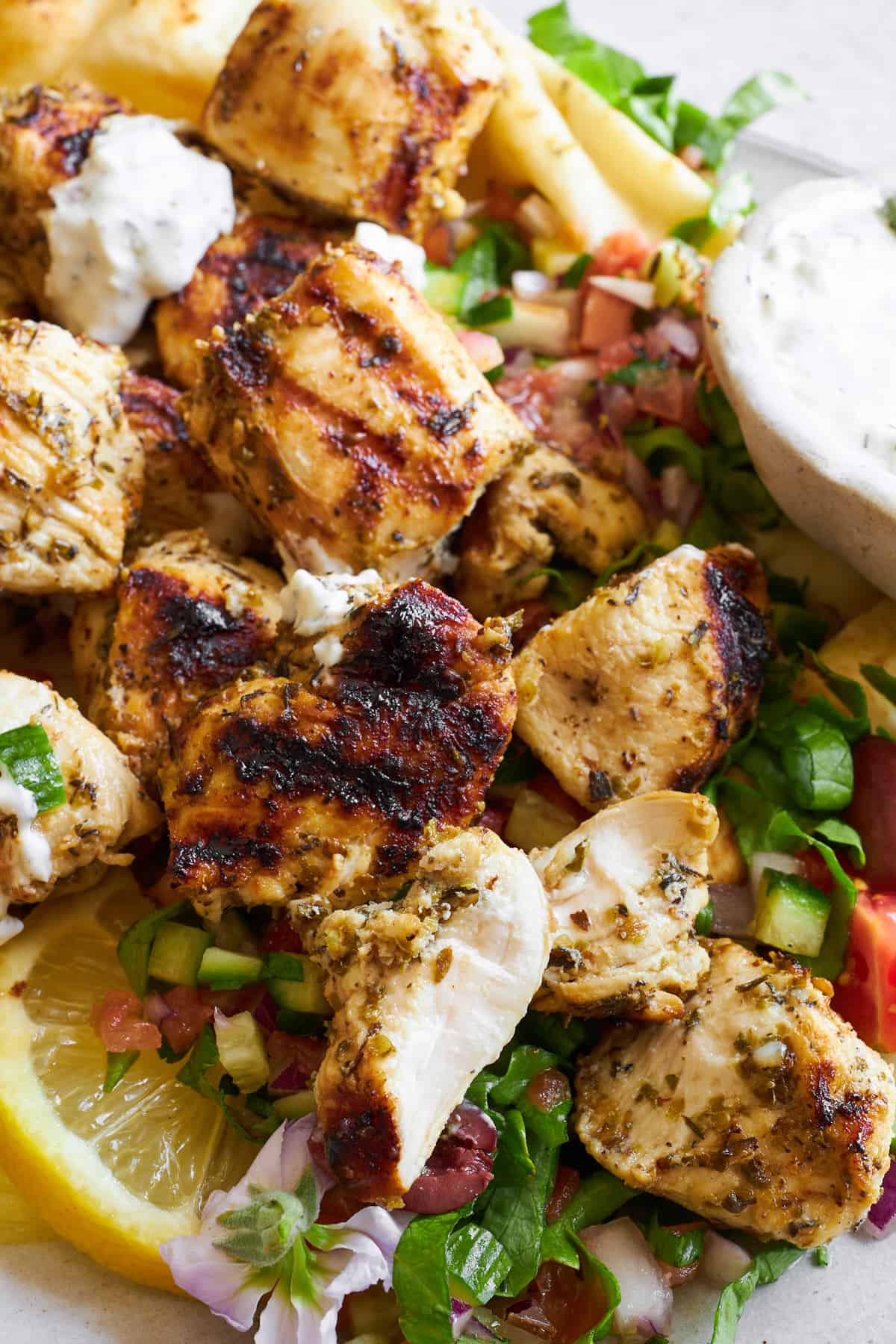 Close up image of Greek chicken souvlaki over shirazi salad.