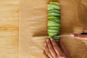 A salmon cucumber roll being sliced.