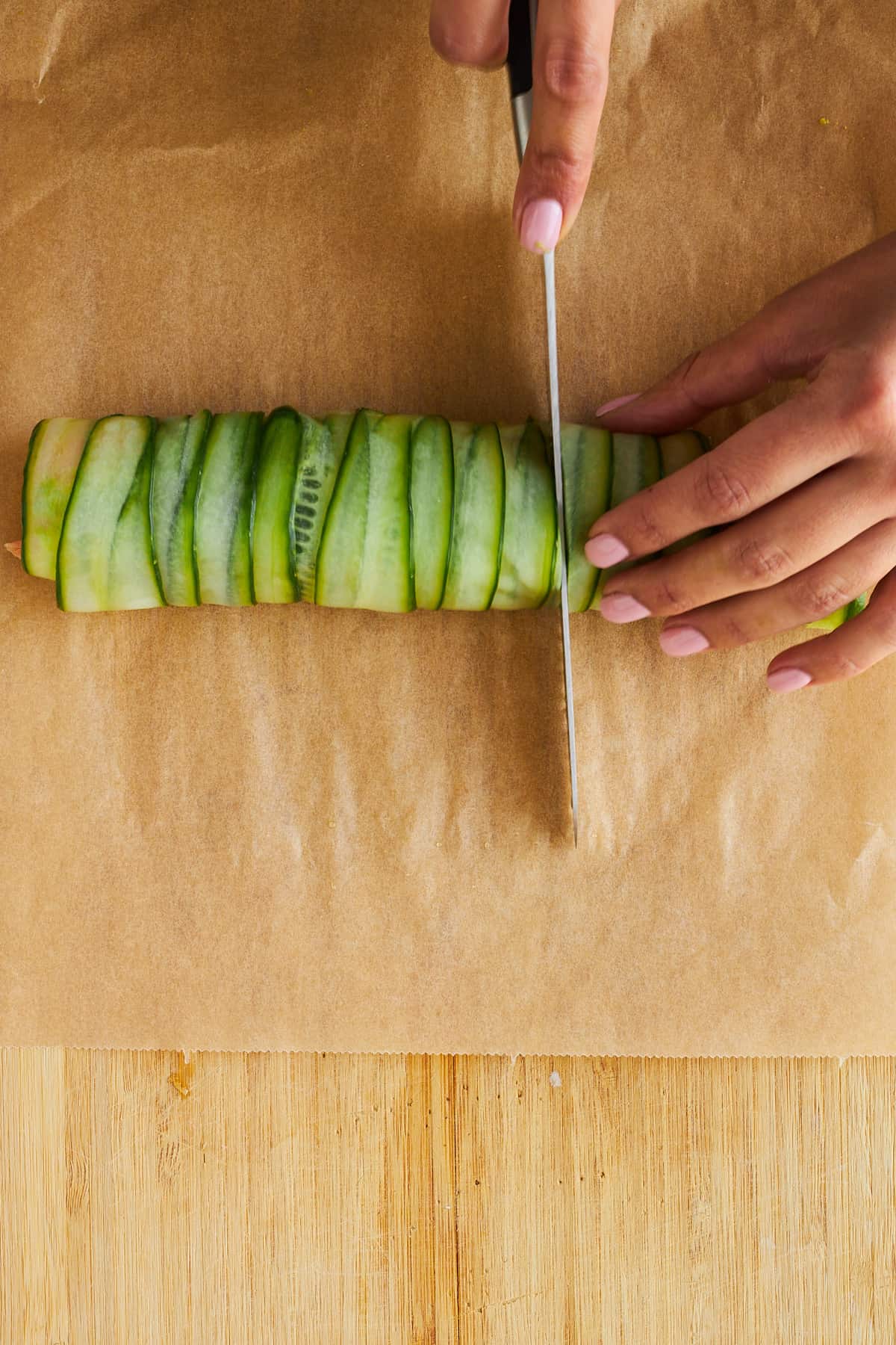 A cucumber roll being sliced into bite-sized pieces. 