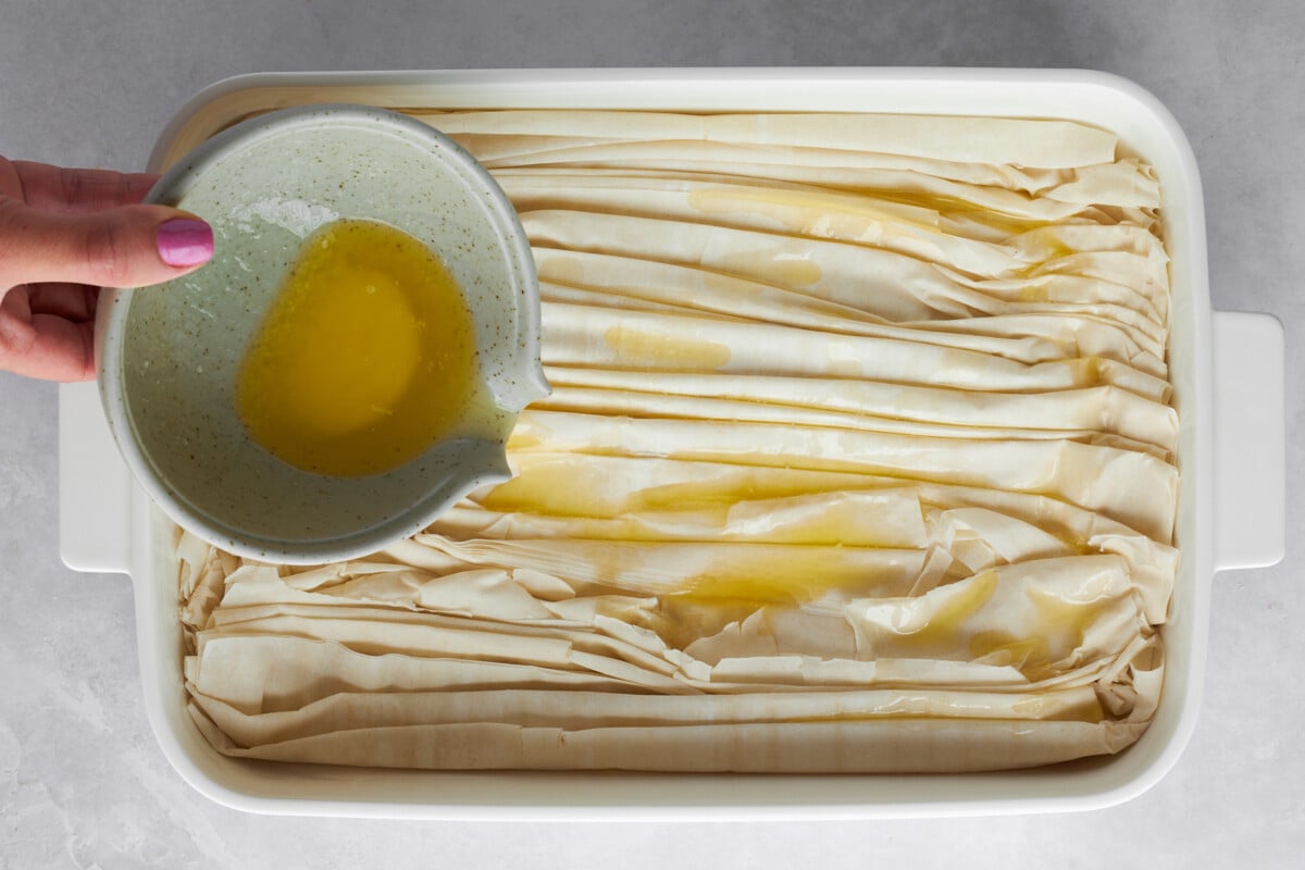 Melted butter being poured over crinkled phyllo dough.