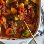 A serving spoon in a casserole dish of baked beef stew.