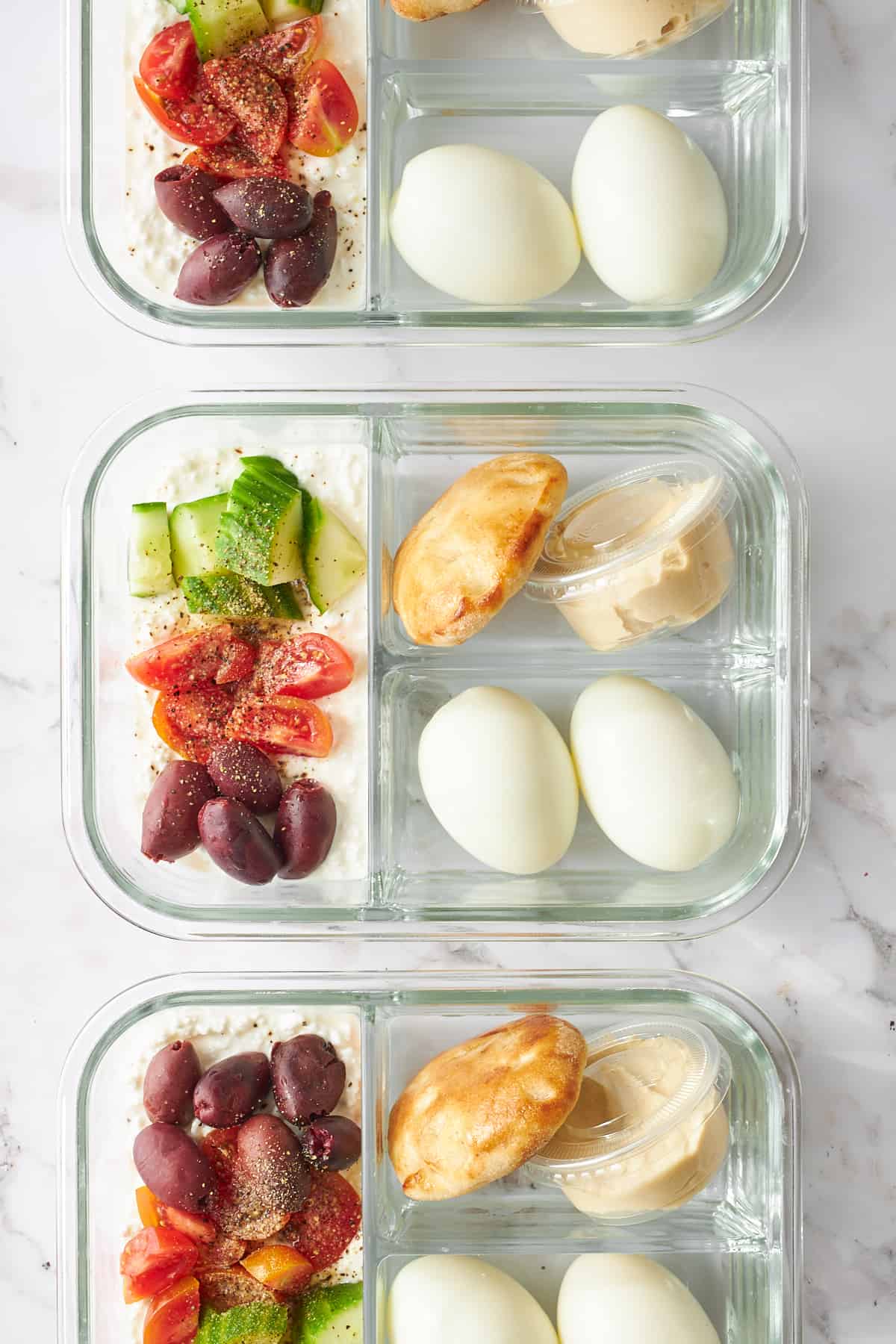 Cottage cheese meal prep jars with eggs, hummus, pita, cottage cheese, and veggies. 