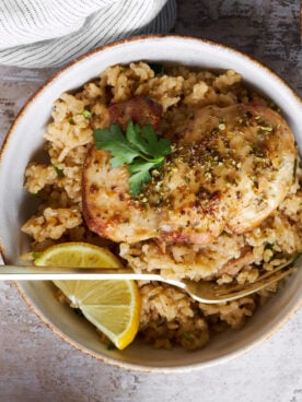 A bowl of Greek chicken and rice with a fork.