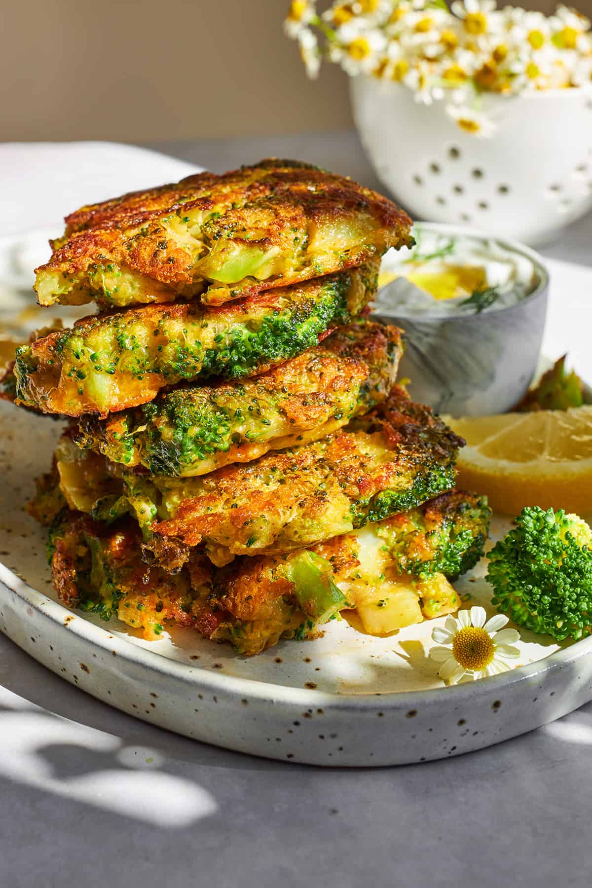 Five cheesy broccoli fritters stacked on top of each other. 