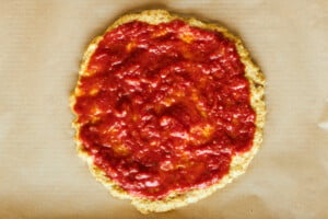 Marinara sauce on chicken pizza crust.