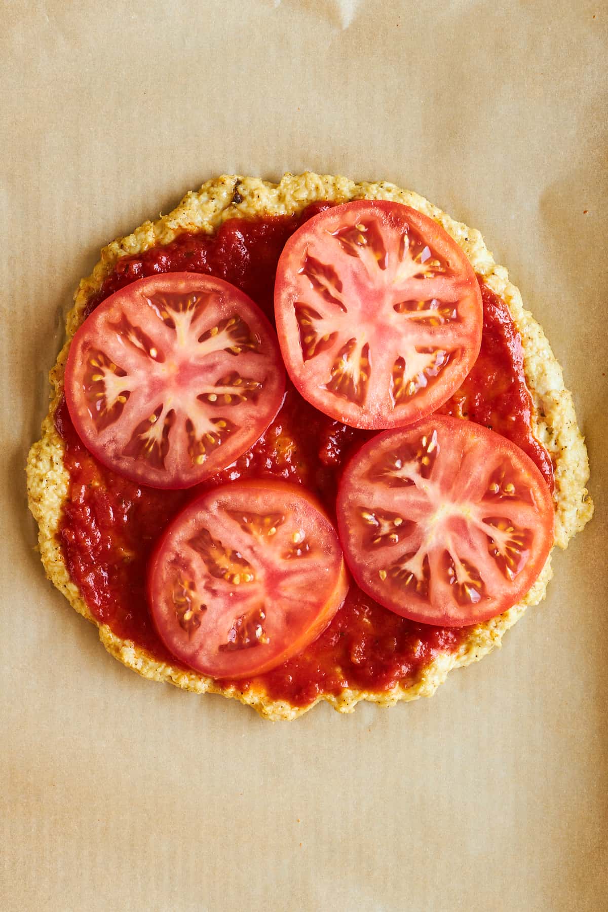 Chicken pizza crust topped with marinara sauce and tomatoes. 