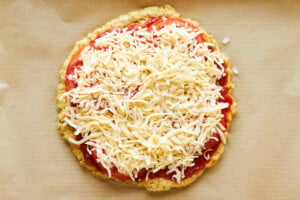 A chicken crust pizza topped with marinara, tomatoes, and cheese.