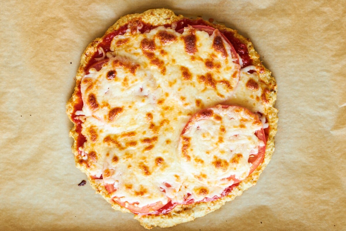 Baked chicken crust pizza with cheese and tomatoes.