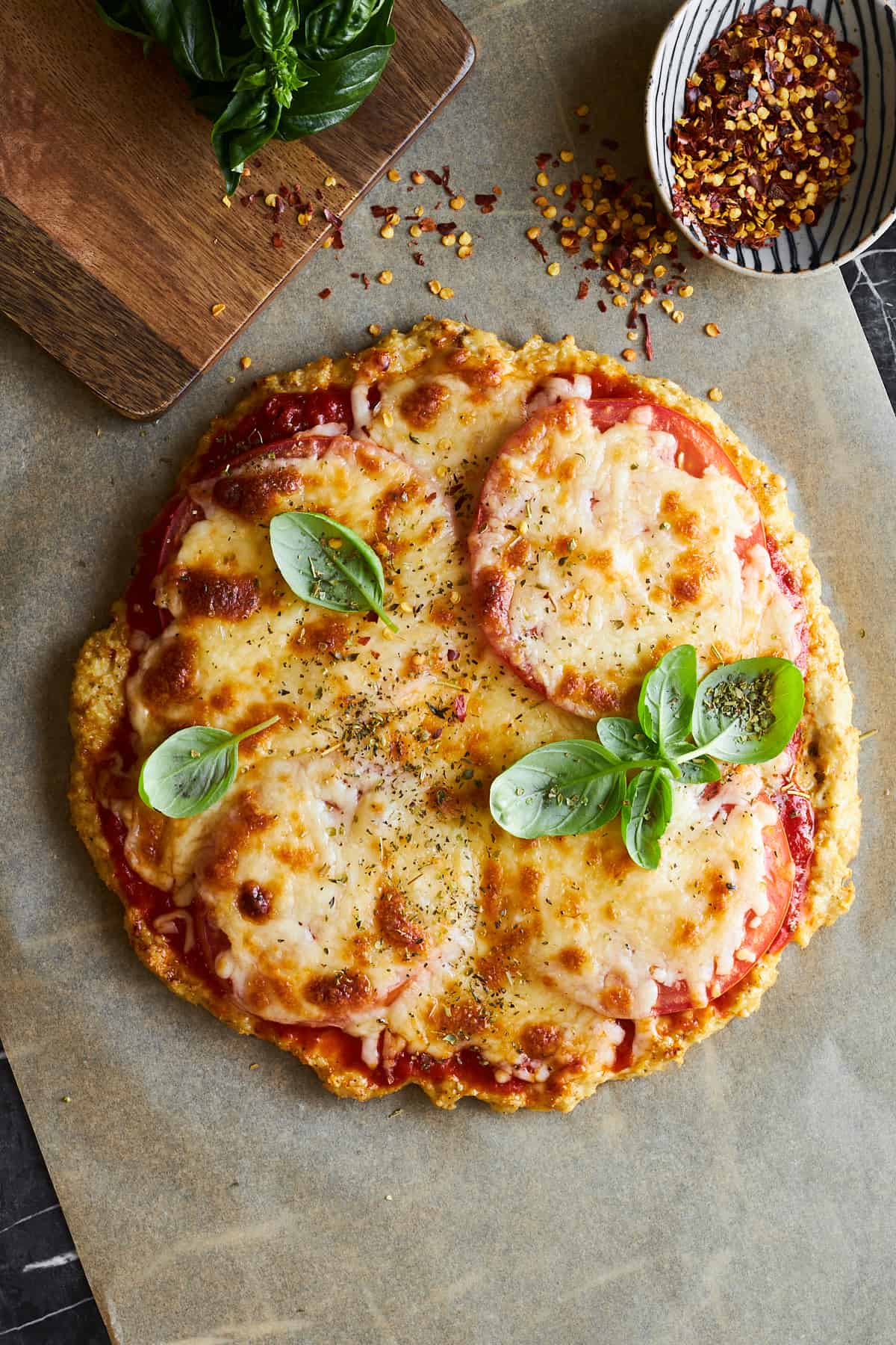 Chicken crust pizza topped with oregano and basil. 