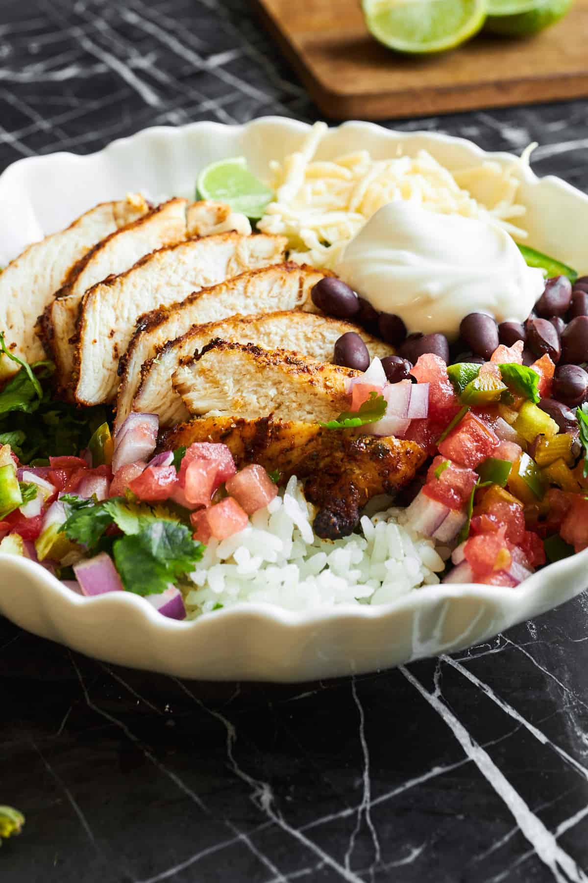 A homemade chipotle chicken burrito bowl with rice, black beans, cheese, salsa, and sour cream. 