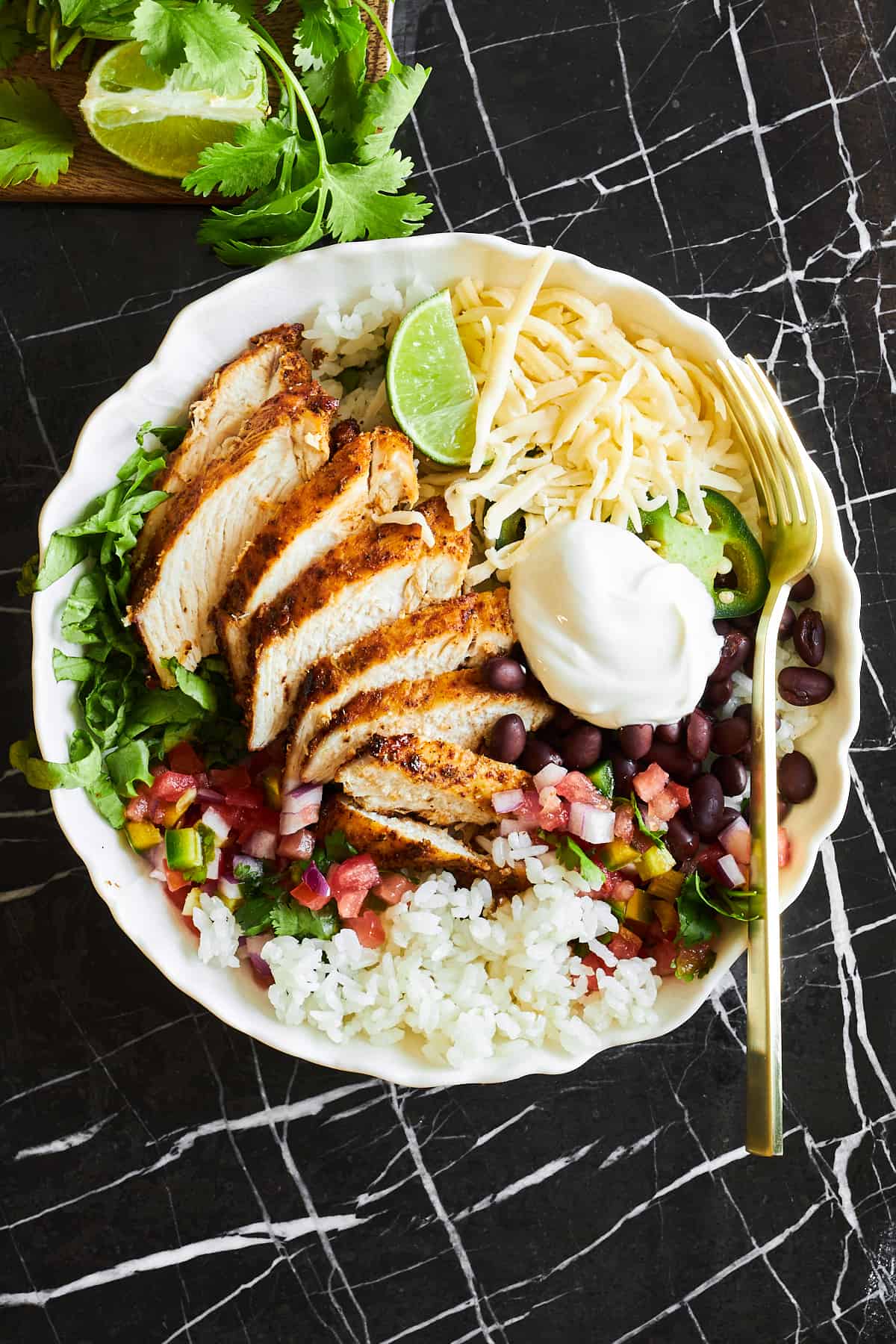 A copycat chipotle chicken burrito bowl with a fork on top. 