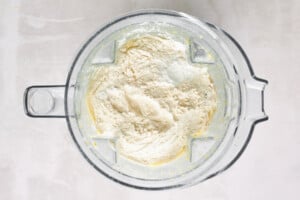 Dry ingredients being added to wet ingredients in a blender.