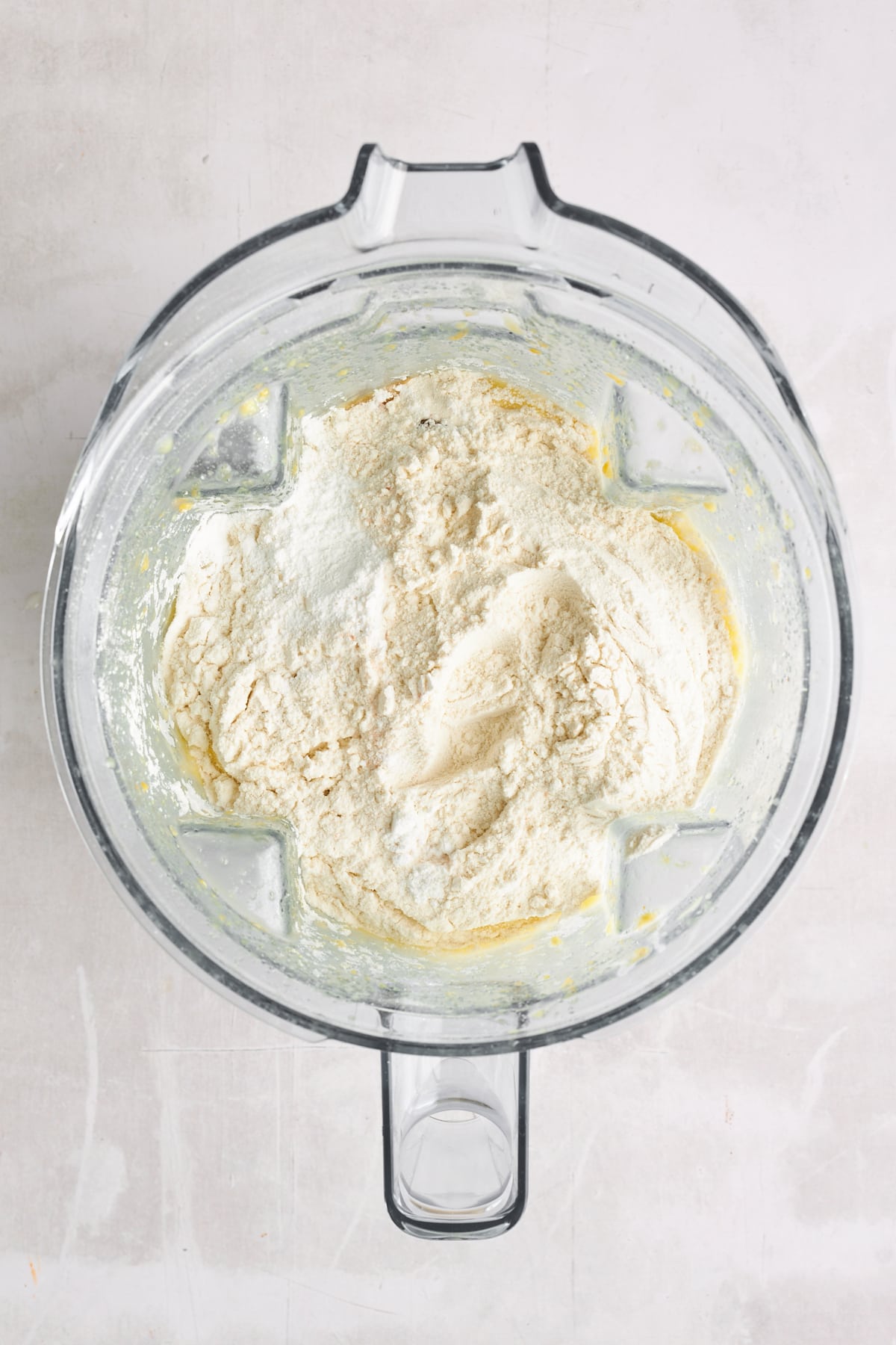 Dry ingredients being added to wet ingredients in a blender. 