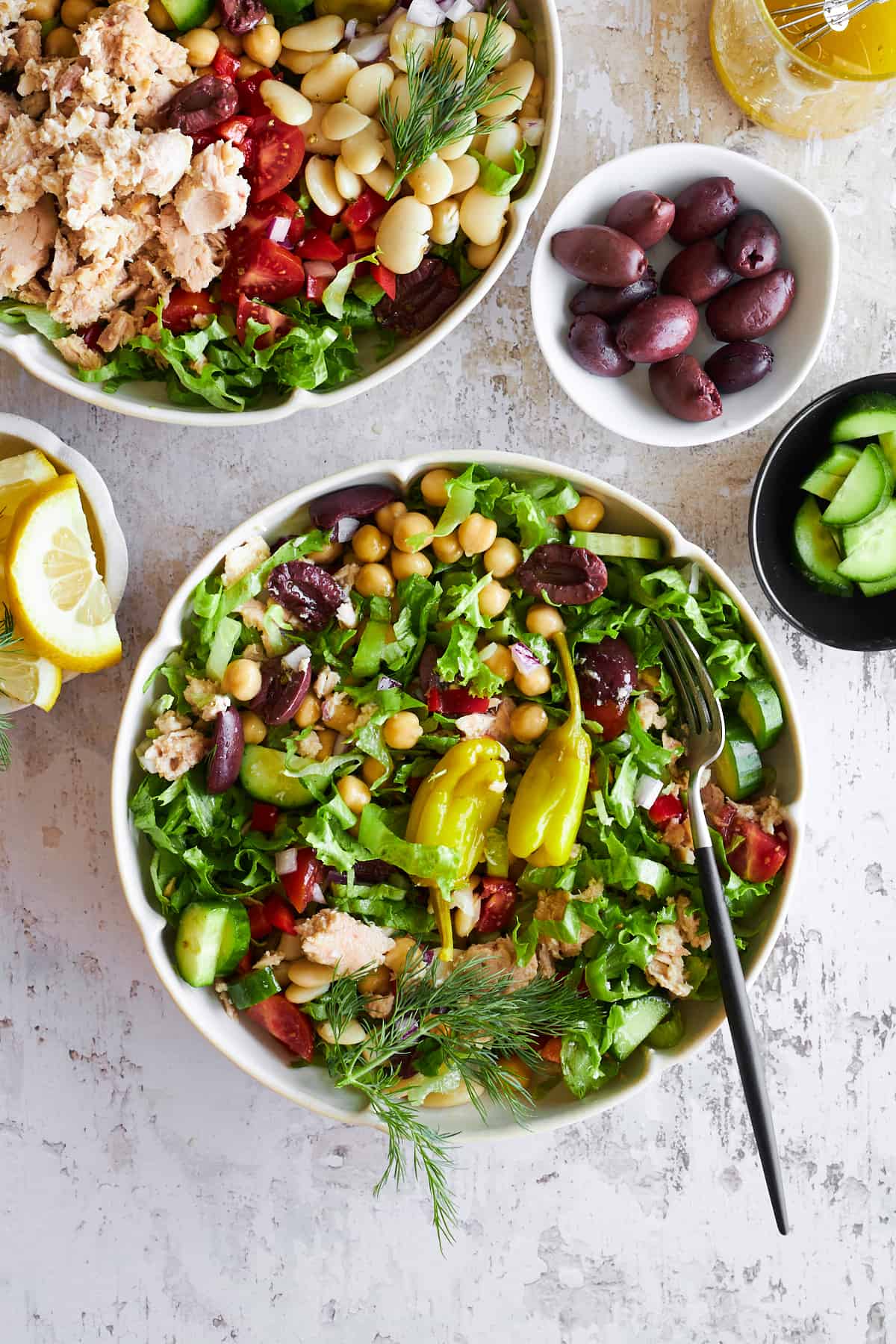 A bowl of Mediterranean tuna salad with two peppers and a fork on top. 