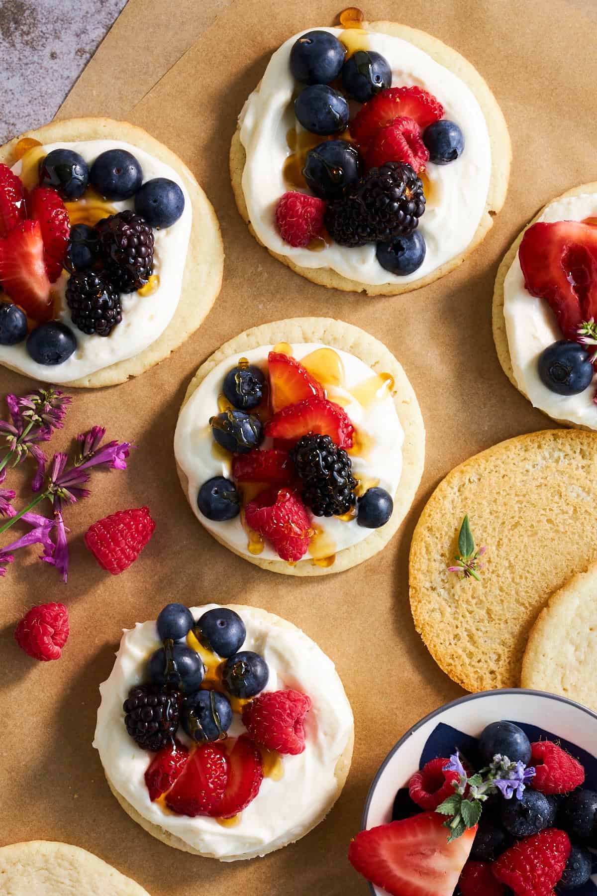 Sugar cookies topped with a cheesecake icing, fresh berries, and honey.