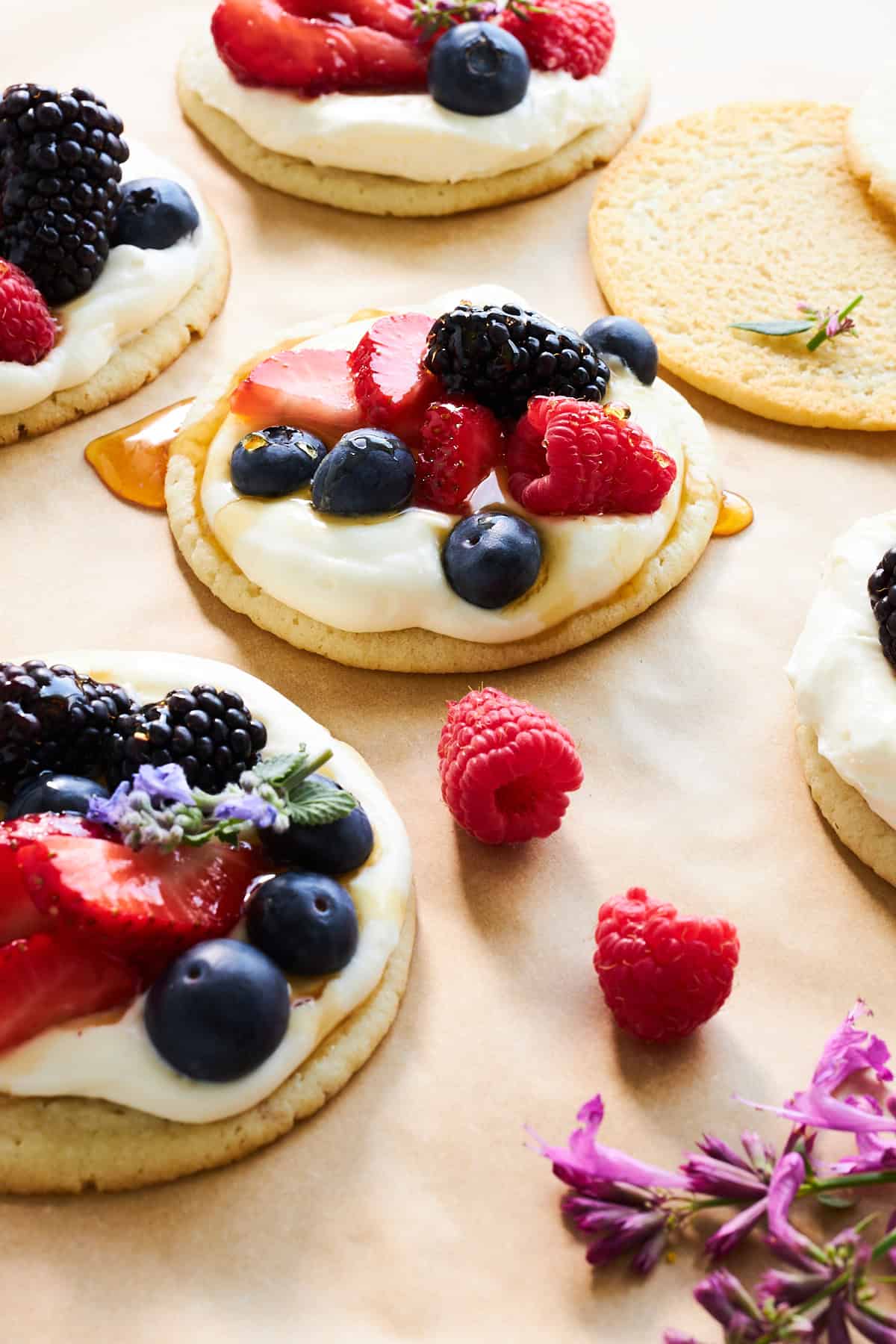 Fruit pizza cookies with cheesecake icing, fresh berries, and honey.