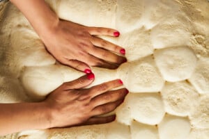 Uncooked dinner rolls being pressed down.