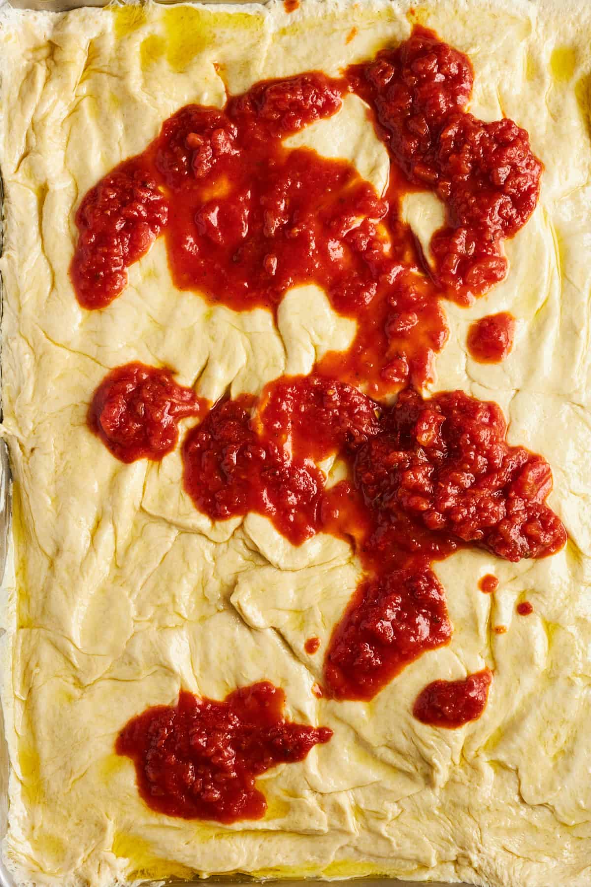 Bread roll pizza crust topped with marinara. 