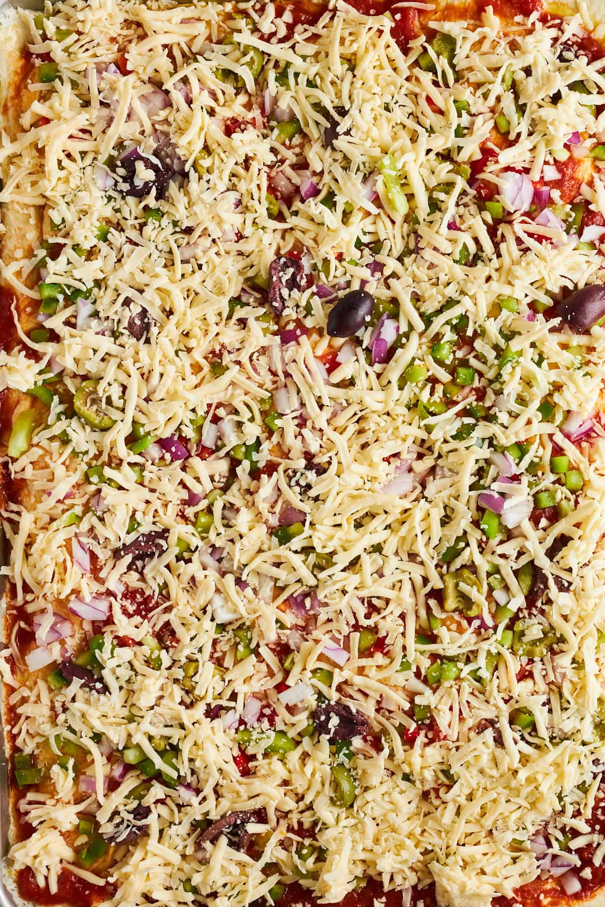 Dinner roll pizza crust topped with marinara sauce, peppers, onions, olives, and shredded cheese. 