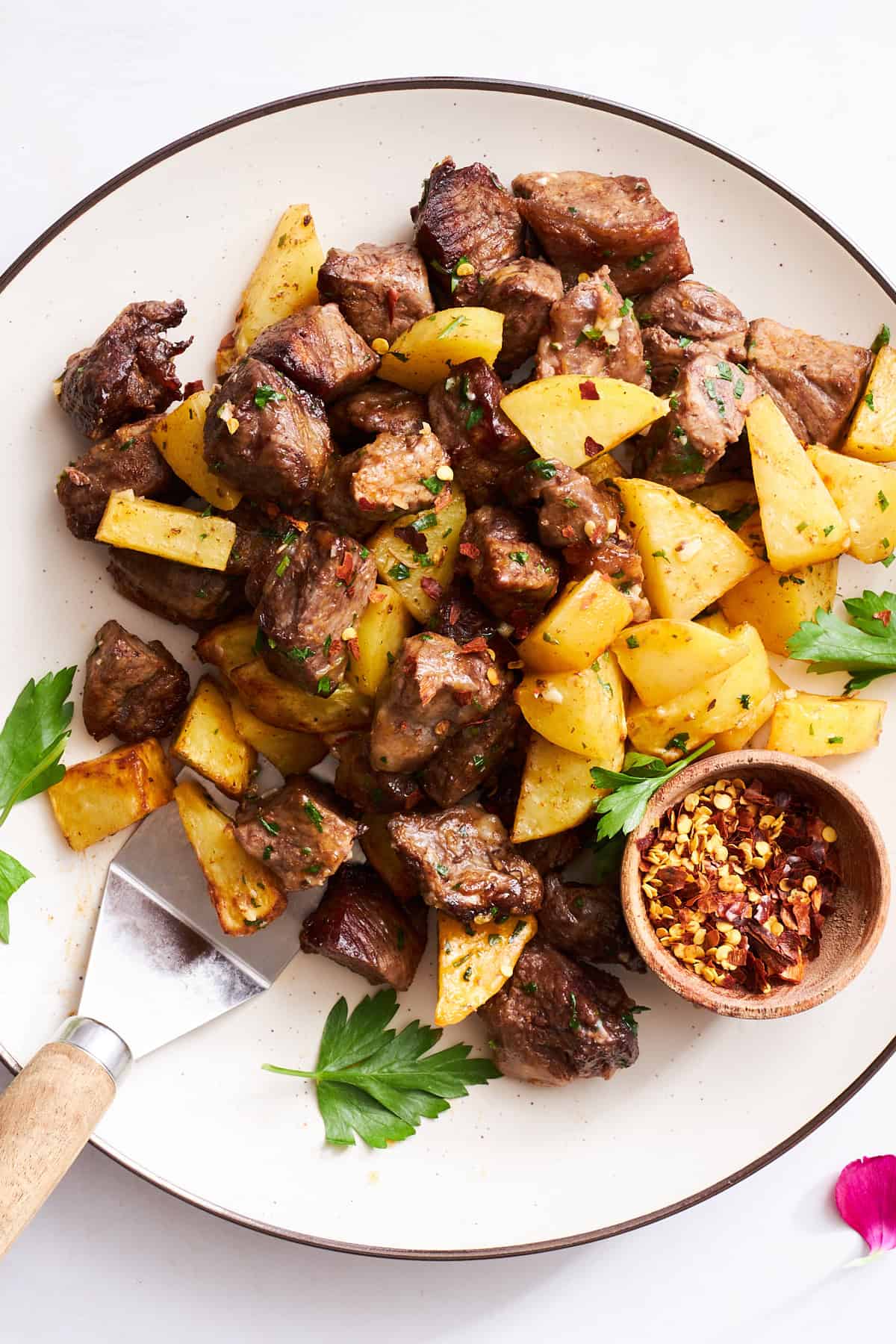 A plate of air fryer garlic steak bites and potatoes.