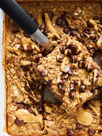 A peanut butter oatmeal bar being lifted from a baking dish.