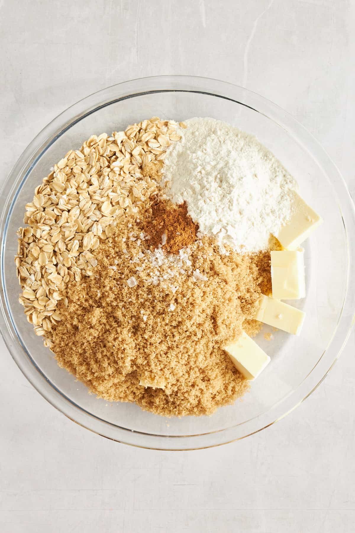 Oats, flour, brown sugar, salt, cinnamon, and butter in a mixing bowl. 