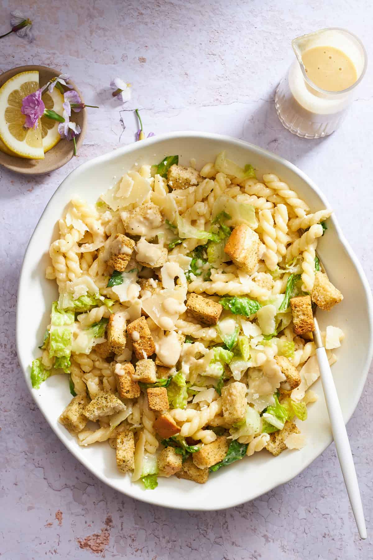 A bowl of Caesar pasta salad with a fork on the side.