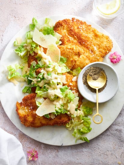 A plate of chicken Milanese topped with Caesar salad.