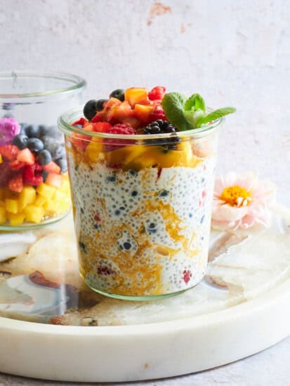 A jar of mango chia pudding topped with fruit salad.
