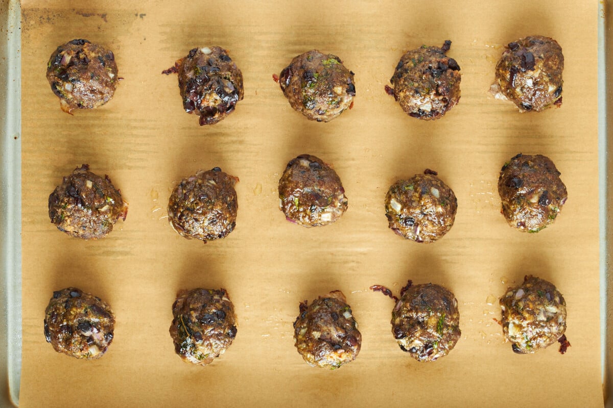 Baked Mediterranean beef meatballs on a baking sheet.