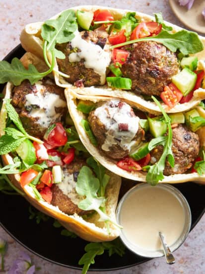 Pita pockets stuffed with Mediterranean beef meatballs, salad, and tahini sauce.