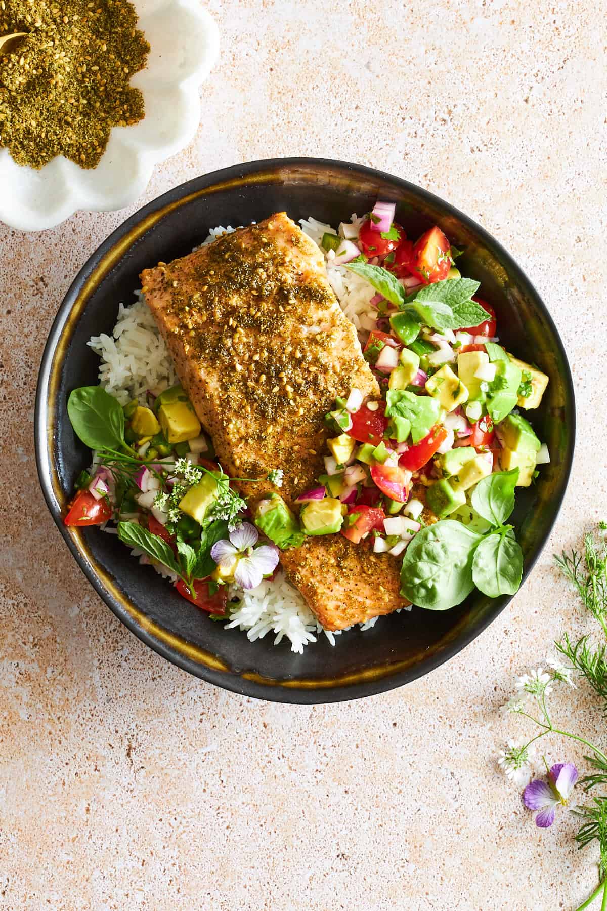 A bowl of white rice with za'atar baked salmon and avocado salsa.